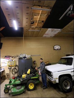 Steve Avers shows where his wife landed after falling through the roof in the garage, which is directly above him and covered with plywood.