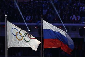 The Russian national flag, right, flies next to the Olympic flag during the closing ceremony of the 2014 Winter Olympics in Sochi, Russia. More than 200 Russian athletes are set to compete in Pyeongchang as an 