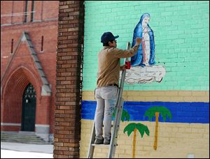 Artist David Cuatlacuatl paints a mural at the Immaculate Conception Church in June. Mr. Cuatlacuatl, whose hometown was in Mexico, died in a car crash in August at age 27.
