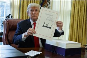 President Donald Trump shows off the tax bill after signing it in the Oval Office of the White House on Dec. 22, 2017.