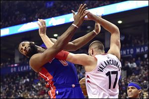 Toronto Raptors center Jonas Valanciunas and Detroit Pistons center Andre Drummond get tangled up under the net battling for a loose ball.