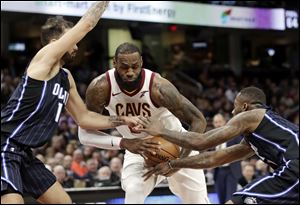 Cleveland Cavaliers' LeBron James, center, drives between Orlando Magic's Evan Fournier, left, and Jonathon Simmons.