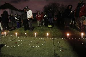 Family and friends gather near candles that spell, 
