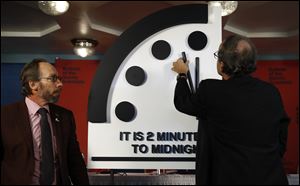 Robert Rosner, chairman of the Bulletin of the Atomic Scientists, right, joined by Bulletin of the Atomic Scientists member Lawrence Krauss, left, moves the minute hand of the Doomsday Clock to two minutes to midnight during a news conference at the National Press Club in Washington, Thursday, Jan. 25, 2018.