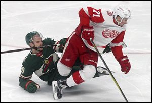 Detroit Red Wings' Dylan Larkin, right, leaves Minnesota Wild's Nate Prosser on the ice after a collision.