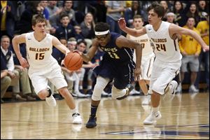 Toledo Christian’s Delano Smith, front, tries to dribble away from Edgerton’s  Clayton Flegal, left, and Tyson Curry during the Eagles’ victory in a Division IV district semifinal at Napoleon High School on Wednesday night.