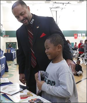 First grader Damon Murdock, 7, who proudly states that he reads at a second grade level, looks at donated books with Superintendent Romules Durant at Old Orchard Elementary School.