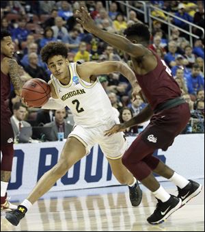 Michigan guard Jordan Poole, left, drives on Montana guard Michael Oguine during the first round of the NCAA Tournament.