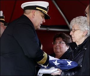 U.S. Navy Rear Admiral Scott Jerabek, left, presents the flag to Joan Stough, right, 84-year-old sister of Ora H. Sharninghouse Jr., during his burial Saturday in Weaver Cemetery.