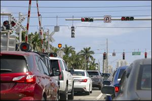Motorists in backed-up traffic disregard a Do Not Stop on Tracks sign in Aventura, Fla. along the Florida East Coast Railway tracks that Brightline trains to and from Miami will begin using later this year. 