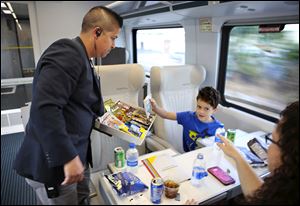 Gavin MacArthur, 8, of Pembroke Pines, Fla., chooses a cookie from a snack tray offered by Brightline train attendant Jose Garcia during a trip from Fort Lauderdale to West Palm Beach, Fla. on March 28, 2018.    