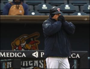 Mud Hens manager Doug Mientkiewicz tries to keep his hands warm while coaching third base Wednesday against the Durham Bulls. 