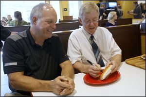 Scott Radel, Vice President of Tony Packo's of Toledo, left, watches as Sylvania Mayor Craig Stough signs a bun during the grand opening of the newest Tony Packo's Restaurant in Sylvania. 