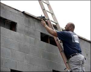 Brandon Mayes, a brick mason with Harper Masonry, gets ready to place a brick at the former Schorling's Market building in Toledo.