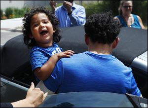 Ever Reyes Mejia of Honduras carries his son to a vehicle after being reunited and released by ICE in Grand Rapids, Mich. They were separated in May.