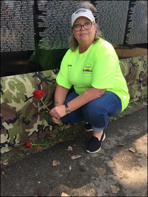 Carole Shadbolt, an Army veteran who served from 1974 to 1976, places a red rose at the Moving Wall. The traveling memorial commemorated casualties from the Vietnam War between 1955 and 1975.