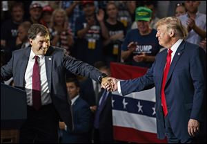 Ohio state Sen. Troy Balderson, left, then a candidate to succeed former Republican U.S. Rep. Pat Tiberi in Ohio's 12th District, clasps hands with President Donald Trump as Balderson speaks during a rally at Olentangy Orange High School in Lewis Center, Ohio Aug. 4. 