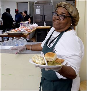 Volunteer Beatrice Davis serves lunch at the Martin Luther King Kitchen for the Poor in Toledo Aug. 7. The kitchen has a goal of raising $15,000 at its Strike Out Hunger! event Sept. 29.