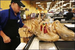 Jason Gray of Toledo bags groceries at Kroger in Toledo on Thursday. Kroger will be phasing out single-use plastic bags in all stores by 2025.