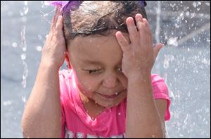 Harmony Sifuentes, 4, of Toledo plays in the Splash Pad Monday at Promenade Park in Toledo.