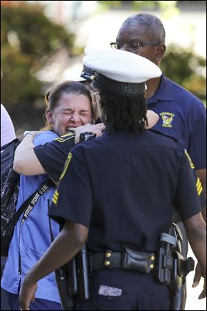 A woman is comforted by authorities after a shooting Thursday in downtown Cincinnati left four people dead.