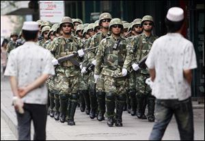 Paramilitary police officers patrol as Uighur men walk by in Urumqi, western China's Xinjiang province, in 2009. 