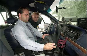 Councilman Mike Edenius uses one of the new laptop computers as police Chief David Graham looks on.