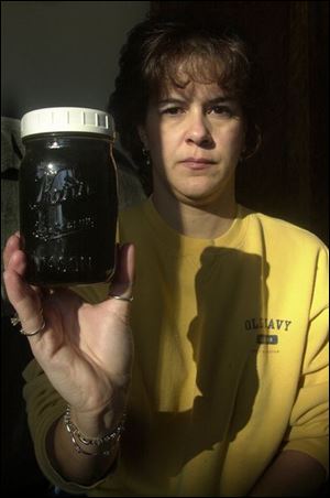Vickie Wilkins of Lambertville, Mich., displays dirty water she removed from one of her filters. She said she is eight signatures short of the number needed to ask for city water.