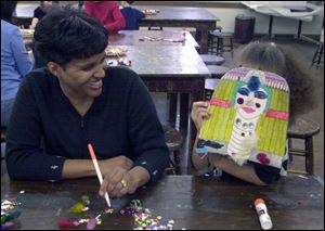 Libby Ball has a laugh has her daughter, Lisanne, 5, tries on her handiwork during a workshop on mummy masks.