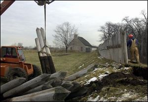 Chuck Richards operates a crane while Jeff Topp of Ohio Building Restoration removes rotting pickets at Fort Meigs State Memorial Park.