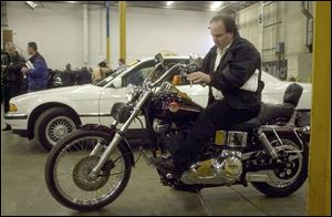 Mike Vampero gets a feel for a Harley Davidson Wide Glide once owned by ex-financier Marty Frankel.