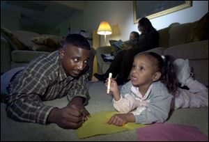Jimmy Hicks helps daughter Jalynn with the alphabet while his wife, Molly, and Jimmy IV read.