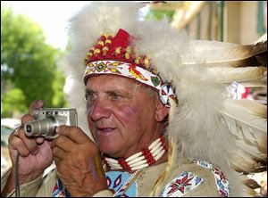 `Chief Mudjaw' - John Sinkovic of West Toledo photographs activity at the Rapid Rally Days, which included tables filled with offerings for shoppers along Main Street. The event continues today in Grand Rapids.