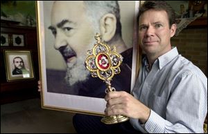Gerard Rusch of Fremont, holding a Padre Pio portrait and relic, is founder and coordinator of the Padre Pio Prayer Group of the Toledo Diocese. The Italian priest, who died in 1968, will be canonized June 16.