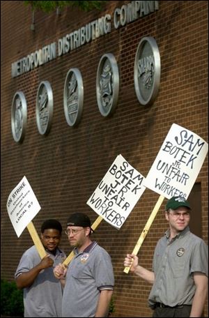 Mike Napolski, left, Bob McGee, and Darrell Wyatt walk the picket line at Metropolitan Distributing Co. on Summit Street.