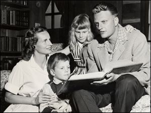 The young evangelist relaxes in a rare moment at home with his wife, Ruth, and the first two of their five children, Franklin, 4, and Ruth, 6.