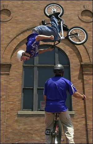 Jacob Marks of Fort Wayne, Ind., does a back flip over teammate Quentin Vestor of Warsaw, Ind., as the High Action Sports Bike team performs stunts on BMXs in Promenade Park during the first TeenFest. CitiFest organized yesterday's event at which hundreds of teenagers listened to bands, showed off tatoos, body-piercings, and hairstyles, and created art. Teens boarded bikes and skateboards and performed stunts and maneuvers to add to the fast-moving event.