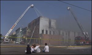 Neighborhood children watch firefighters as they battle the hot spots in the Doeshire building on West Tiffin Street in Fostoria.