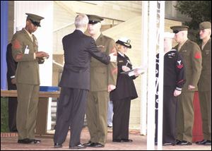 Navy Secretary Gordon England offers congratulations and a medal to Sgt. Michael Farrington of Adrian, Mich.