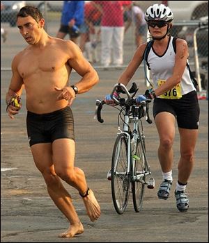 A swimmer and a biker reach an exchange area during yesterday's Sylvania Triathlon at Olander Park. Over 400 athletes participated.