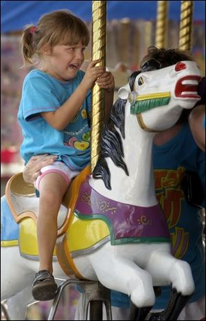 REG fair16p 081602 B August 16, 2002-- Riding the Merry-Go-Round wasn't as fun as it looked for Mamie Opal Hughes, 5. The Lima youngster made it around once before demanding to get off the ride at the Allen County Fair in Lima Friday. Her mother Delores Sowders did convince her to try sitting in the carriage though and that seemed to do the trick as she was all smiles the rest of the way. Blade photo by Andy Morrison