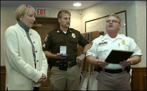 Janice Cook is presented with a Citizen's Lifesaving Award by Sgt. Robert Colwell and police Chief Gary Copeland, right, at the Sylvania Township trustees' meeting.