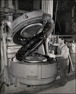 A worker removes a heavy-duty tire from a curing mold at a Firestone plant in Akron, once the world's rubber capital.