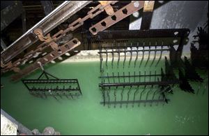 Parts are lowered into a bath as they move down the line at MetoKote's factory in Monclova Township.
