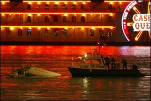 A fire boat keeps watch on wreckage of a Grand Aire plane floating down the Mississippi River. Both pilots were rescued.