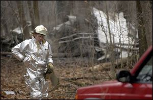 Master Sgt. Mike George, fire chief of the 180th Air National Guard, works at the crash site in Oak Openings Preserve Metropark.