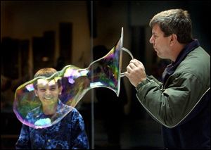 Mekkel Richards, 11, is all smiles as he watches Tom Sklar blow an oversized bubble at COSI-Toledo. The two were among a group of Brooklyn Elementary pupils, staff, and parents on a field trip to the science museum yesterday.

