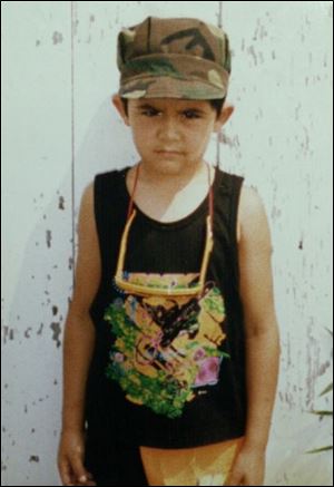 At age 6, Juan wears a fatigue cap and stands at attention. He always wanted to be a Marine, his wife said.