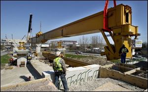Two cranes, working in tandem, hoist into place one of the southbound `underbridge' beams of the new I-280 bridge.