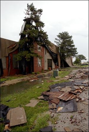 Roofing materials from Bowling Green State University's TEchnology Annex litter the ground and adjacent trees.